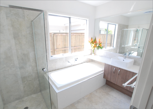 A modern bathroom with a glass shower unit, large white bathtub and good natural lighting from windows.