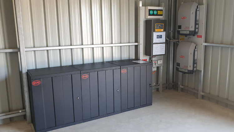 Large boxes housing the batteries, with invertor boxes on the wall nearby, with connections to the solar PV system.