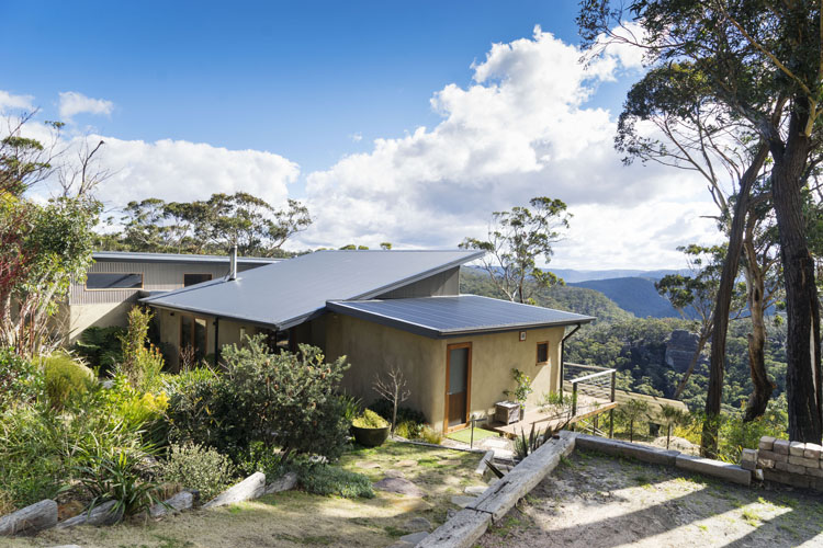 A photo of a straw bale home in the bush. The straw bales are rendered to provide a smooth surface.