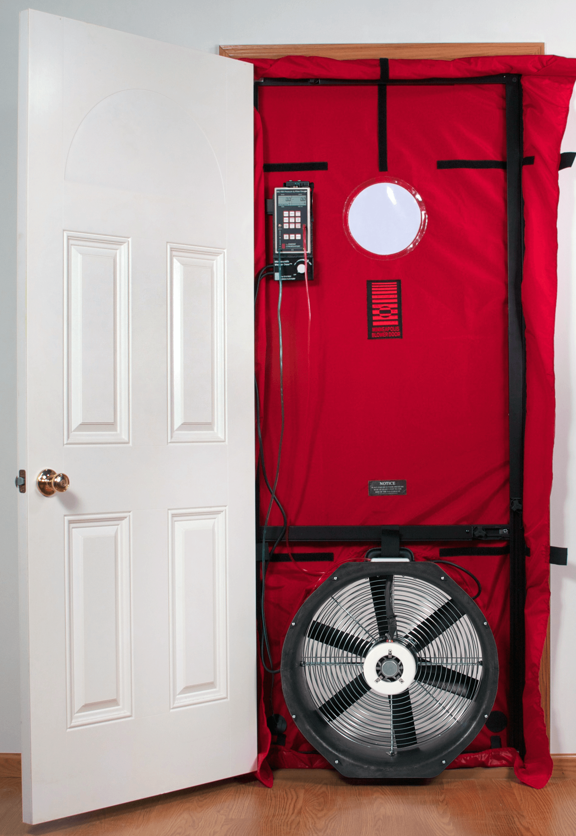 A blower door tester is installed in a door way which consists of a frame and a flexible panel fitted in the doorway with a fan and an air pressure gauge.